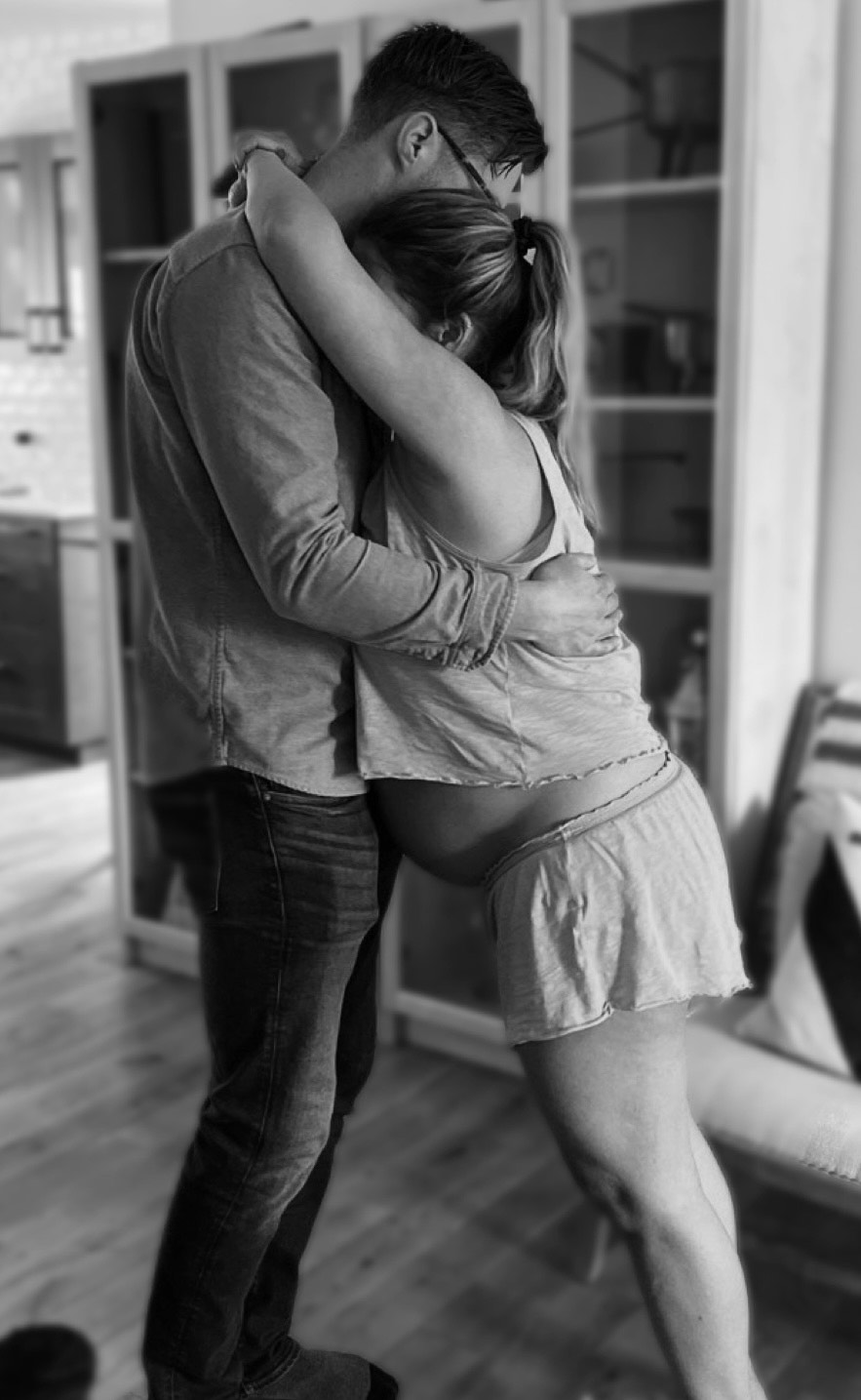 An expecting couple holding each other at home